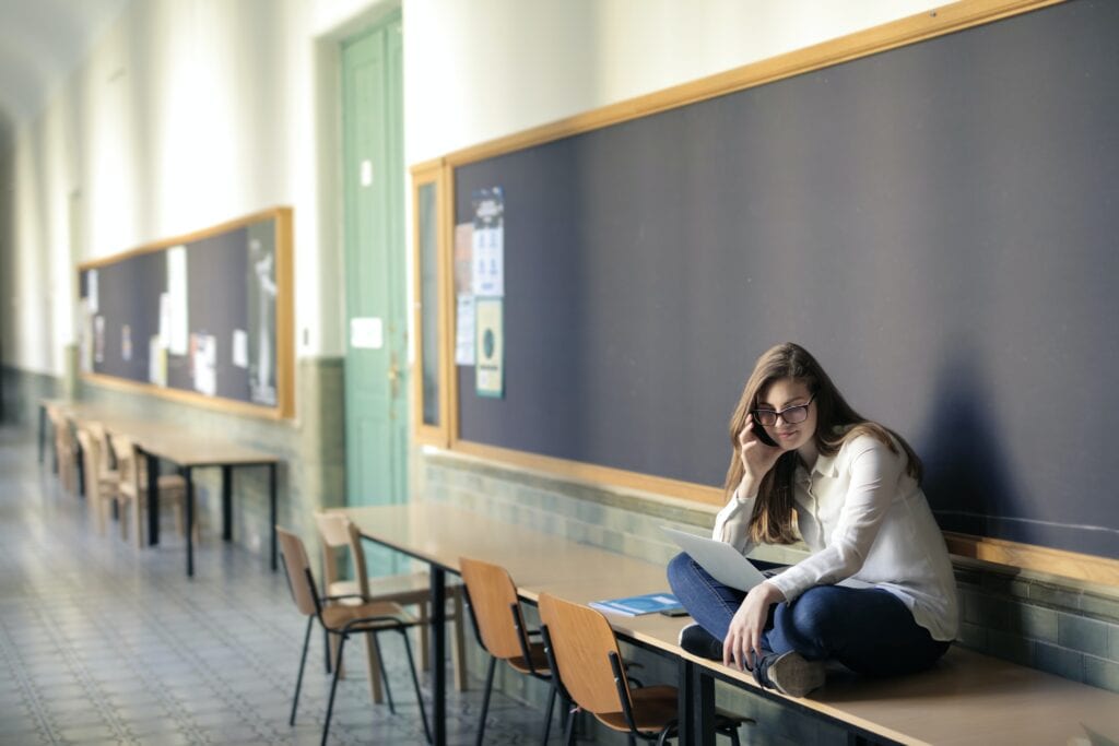 a girl sitting alone on a table at school, she is lonely with no friends