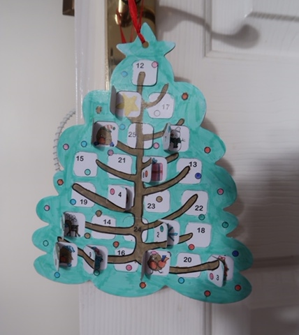 picture of a paper Advent calendar from The Works hung on a white door with gold door handle