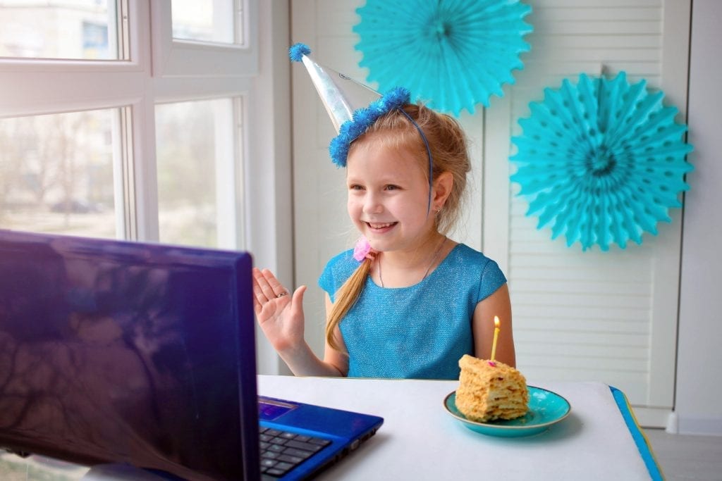 Happy girl  sibling celebrating birthday via internet in quarantine time, self-isolation and family values, online birthday party. Congratulations animator via laptop, online. Stay at home