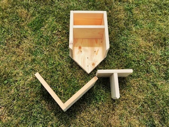 more pieces of wood stuck together including roof on a grass lawn
