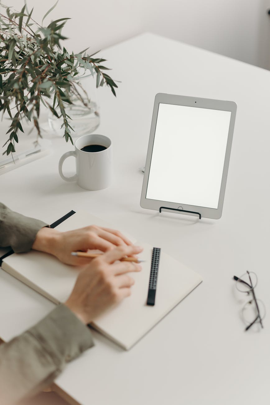 person writing on white paper on white table 50 Productive Things To Do When You’re Bored
