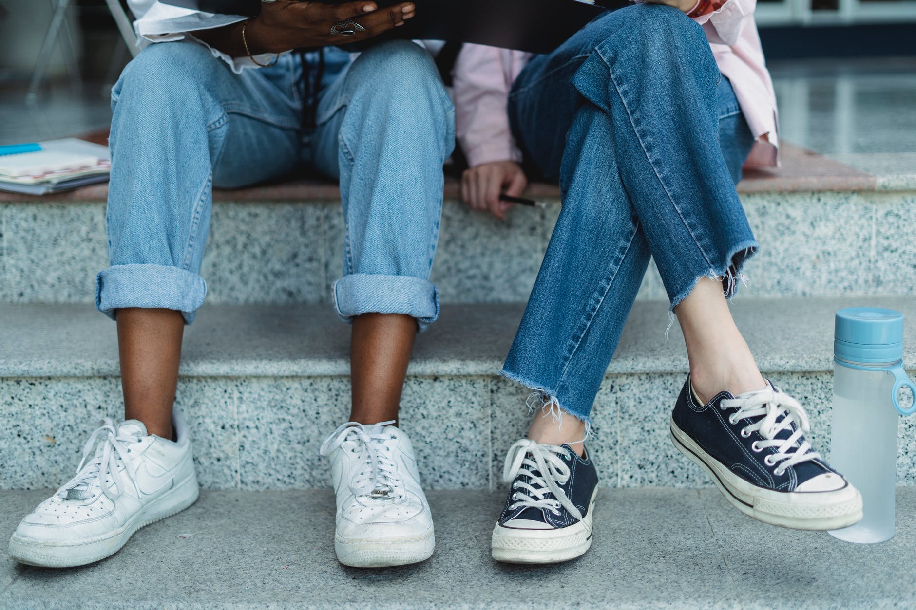 crop multiracial students studying on staircase in town