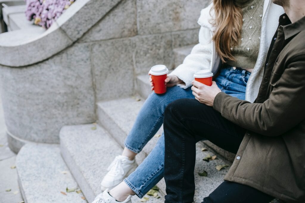 the legs of two people who are sat on steps with a soft drink in their hand. They are demonstrating how to talk so kids will listen.