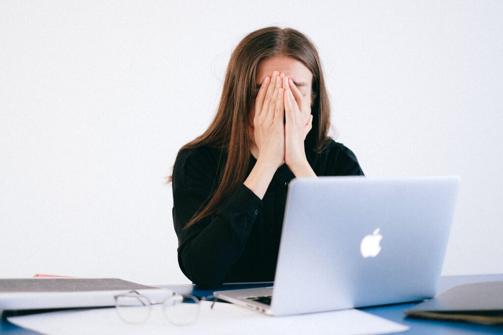 teenage stress, girl has head in her hands looking at laptop
