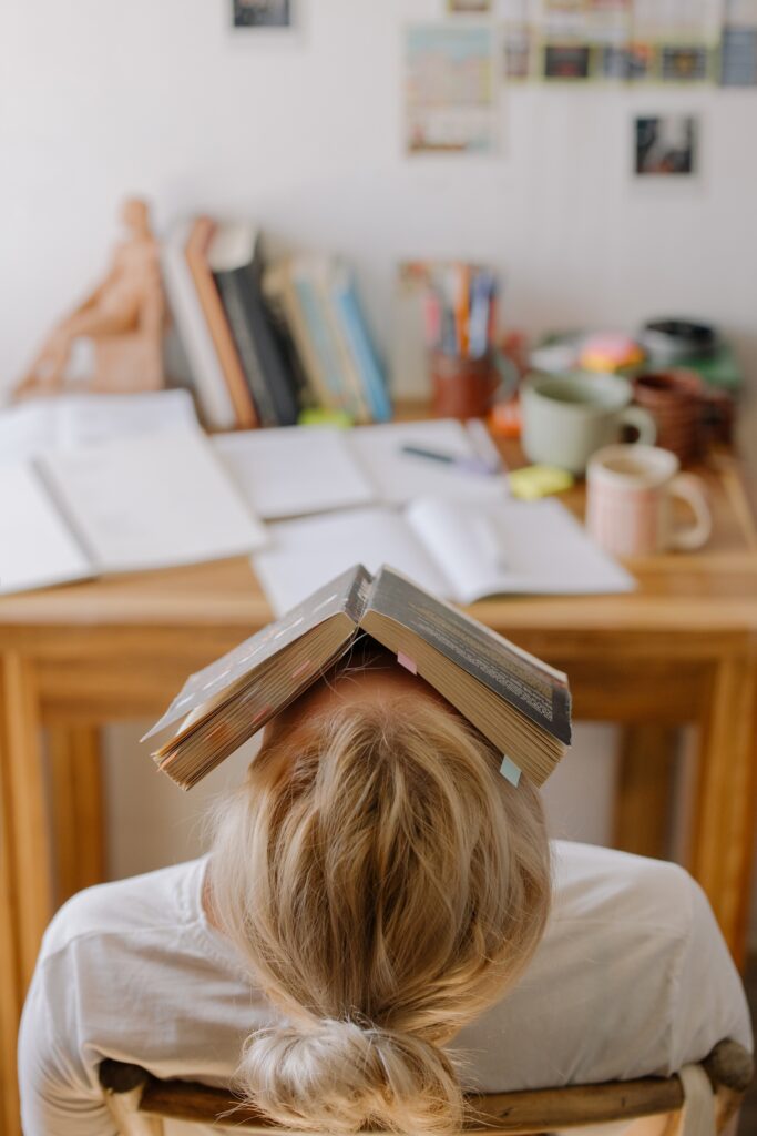 teenage stress, girl balancing book over her head as she is exhausted